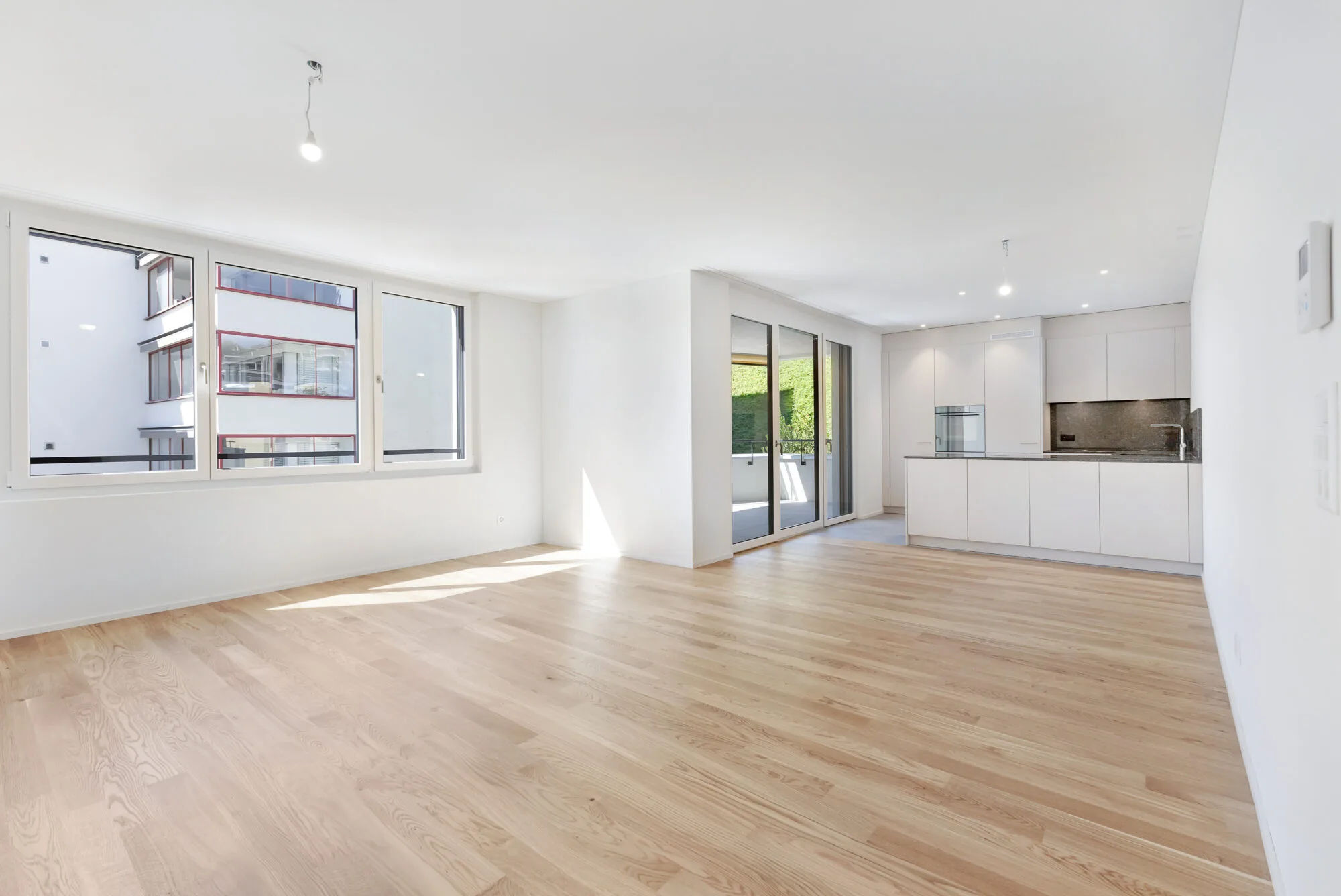 Leere moderne Wohnung mit Holzboden und großer Fensterfront.